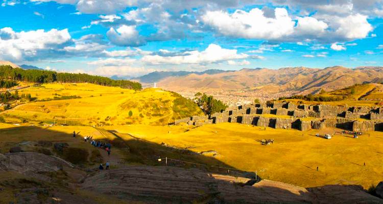 Weite goldene Landschaft der Sacsayhuamán-Ruinen mit Blick auf Cusco unter vereinzelten Wolken