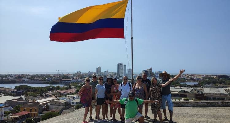 Groupe de touristes posant avec énergie sous le drapeau colombien avec la ligne d'horizon de Carthagène en arrière-plan