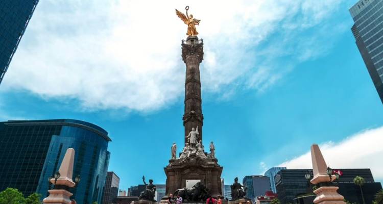 De Engel van de Onafhankelijkheid kolom van Mexico-Stad rijst dramatisch op tegen een levendige blauwe hemel en moderne torens.