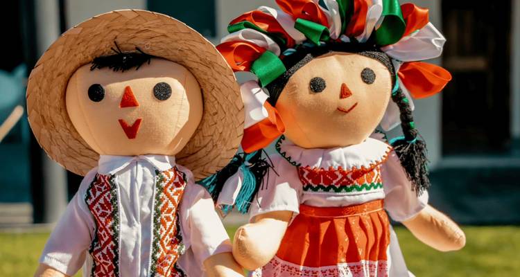 Close-up of two brightly dressed traditional rag dolls with embroidered outfits and ribboned headdresses.