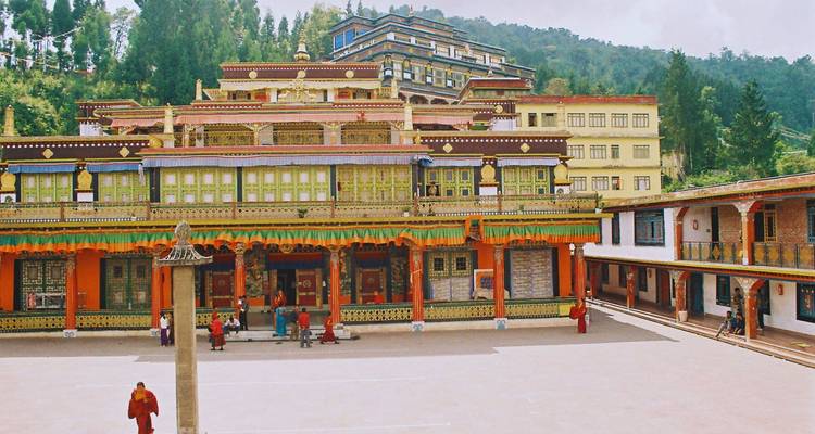 Farbenfroher buddhistischer Klosterhof mit Mönchen und Besuchern unter den bewaldeten Hügeln von Sikkim.