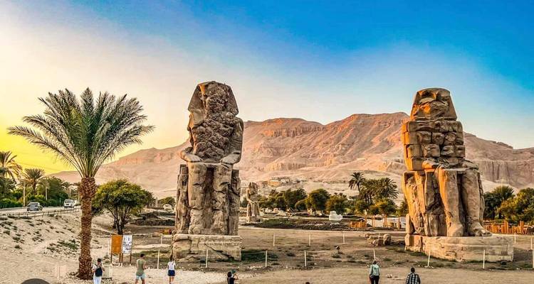 Las estatuas de los Colosos de Memnón se alzan contra las montañas del desierto al cálido atardecer