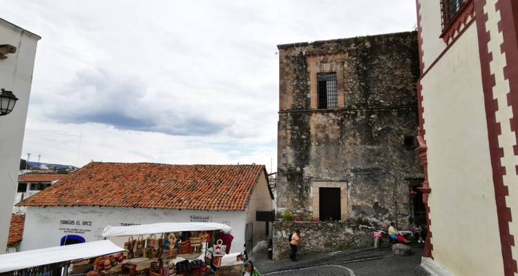 Verwitterte Steinkirchenwand und Ziegeldächer auf einem Marktplatz in einer Bergstraße in Taxco