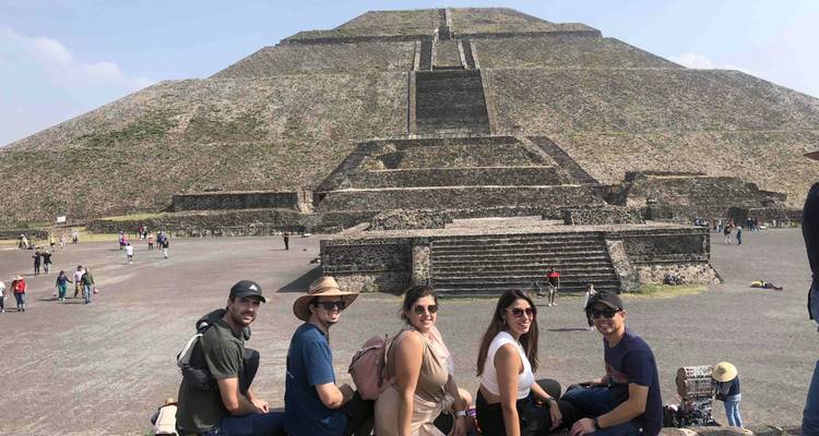 Fünf Freunde sitzen zusammen mit der Mondpyramide, die hinter ihnen in Teotihuacán aufsteigt.