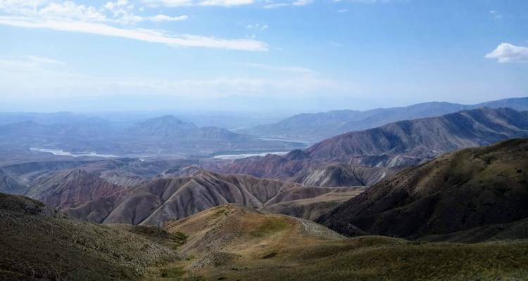 Vista panorámica de cordilleras estratificadas y multicolores con lechos de ríos serpenteantes.