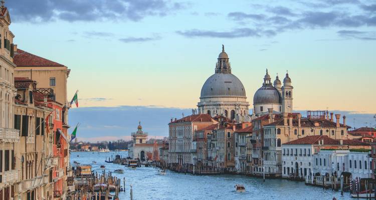 El Gran Canal de Venecia resplandece al anochecer con Santa María della Salute silueteada contra el cielo pastel.