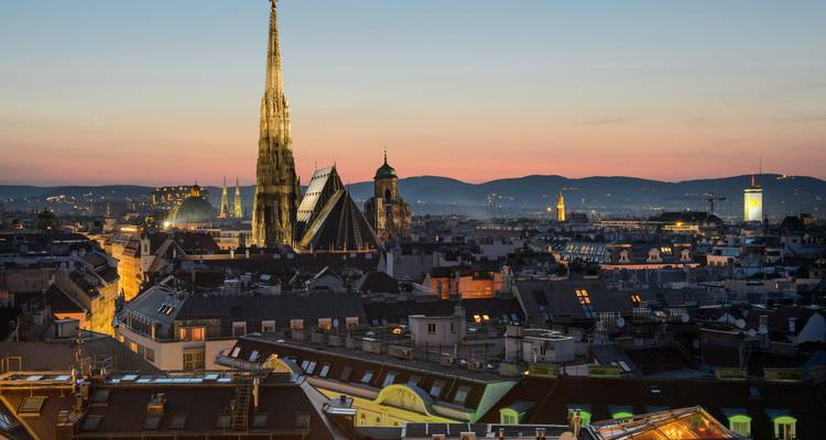El horizonte de Viena al atardecer presenta la aguja de la Catedral de San Esteban iluminada sobre los tejados históricos.