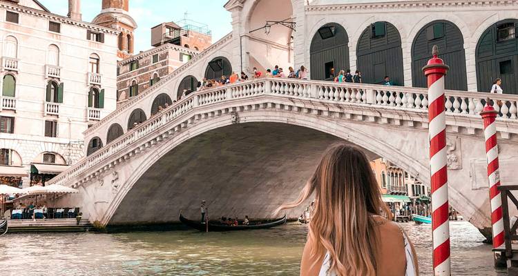 Vista del Puente de Rialto sobre el Gran Canal en Venecia con una viajera en primer plano.
