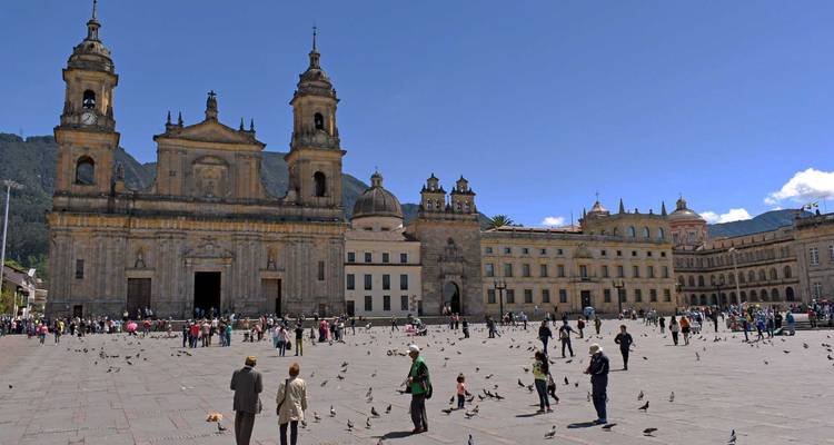 Vue panoramique de la Plaza Bolívar à Bogotá avec la grande cathédrale en pierre et les bâtiments gouvernementaux encadrant la place où de nombreux habitants et pigeons se rassemblent.