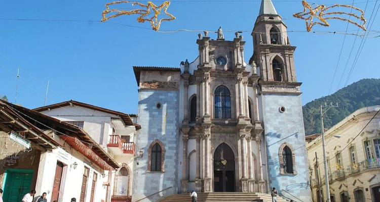 Iglesia de piedra con torres campanario gemelas sobre un cielo azul claro matutino