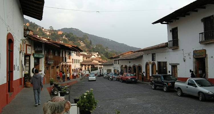 Calle principal empedrada de un pueblo de montaña bordeada de casas coloniales y lugareños
