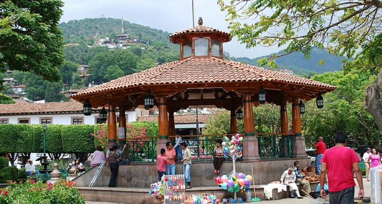 Glorieta central en una plaza del pueblo rodeada por montañas y lugareños vendiendo globos