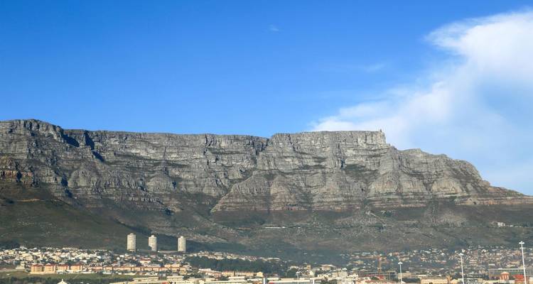 La cima plana de Table Mountain se alza sobre el paisaje urbano bajo un cielo azul brillante.