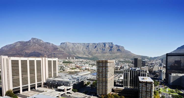 Una vista clara sobre edificios de oficinas de gran altura hacia la amplia cara de Table Mountain bajo un sol brillante.