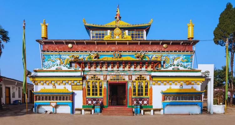 Leuchtend bemaltes buddhistisches Kloster mit kunstvollen Schnitzereien und lebendigen Farben vor einem klaren blauen Himmel.