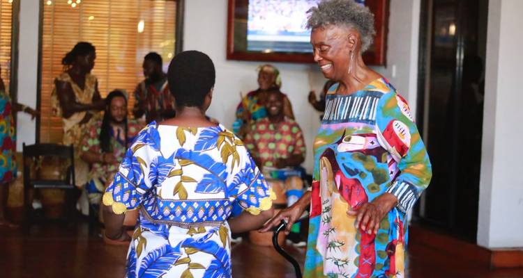 Les voyageurs âgés apprécient la danse traditionnelle à l'intérieur d'un centre culturel, vêtus de vêtements aux motifs colorés.