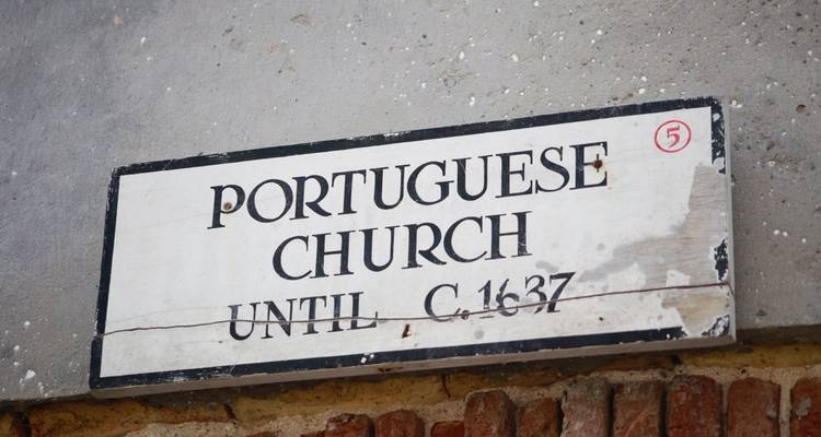 Gros plan d'une vieille pancarte lisant « Église portugaise jusqu'environ 1637 » clouée à un mur.
