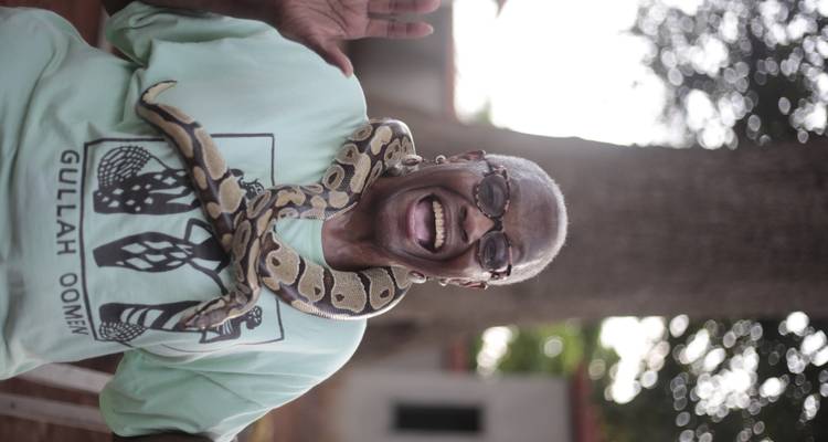 Femme riant avec un serpent vivant drapé autour de ses épaules lors d'une rencontre interactive avec des reptiles.