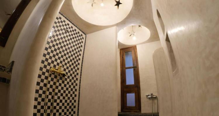 Baño elegante con pared de ducha a cuadros, tragaluces circulares y accesorios de latón