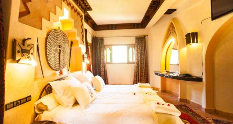 Elegante habitación de hotel de estilo marroquí con yesería ornamentada, iluminación cálida y textiles coloridos