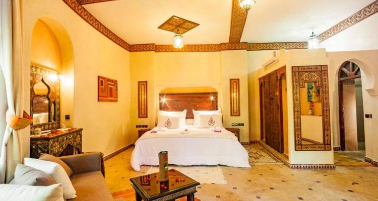 Amplia suite con detalles tallados en madera, linternas y una cama king decorada con pétalos de rosa
