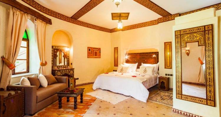 Dormitorio marroquí acogedor con rincón de sofá, espejo grande y vigas decorativas en el techo