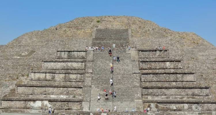 Nahaufnahme einer Stufenpyramide in Teotihuacán mit Besuchern, die die zentrale Treppe hinaufsteigen