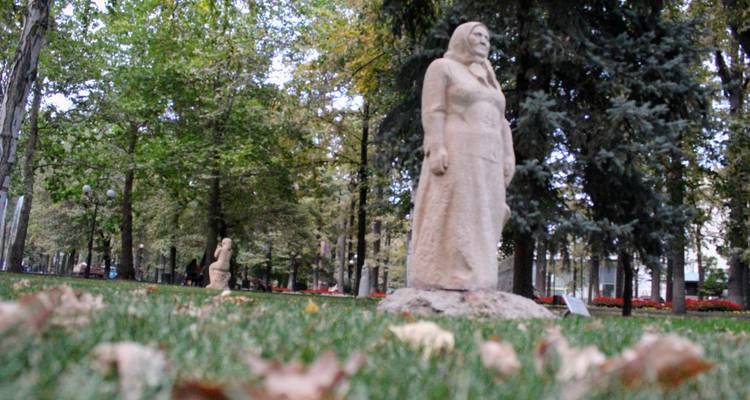 Steinskulpturen, die in einem blätterreichen Stadtpark stehen, aufgenommen mit geringer Schärfentiefe.