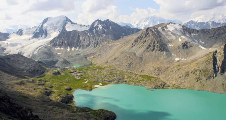 Lago alpino turquesa rodeado de escarpados picos nevados cerca de Karakol en Kirguistán.