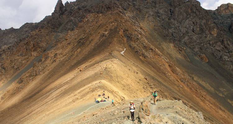Excursionistas atravesando una cresta montañosa afilada de roca multicolor cerca de Karakol.