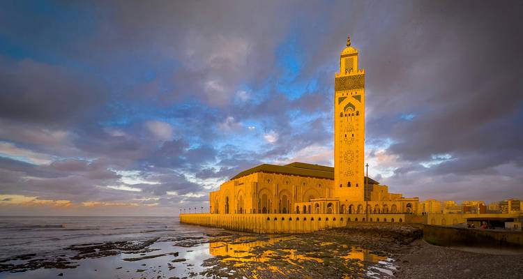 Hassan II Moskee die in warm avondlicht gloeide naast de Atlantische Oceaan met dramatische wolken erboven