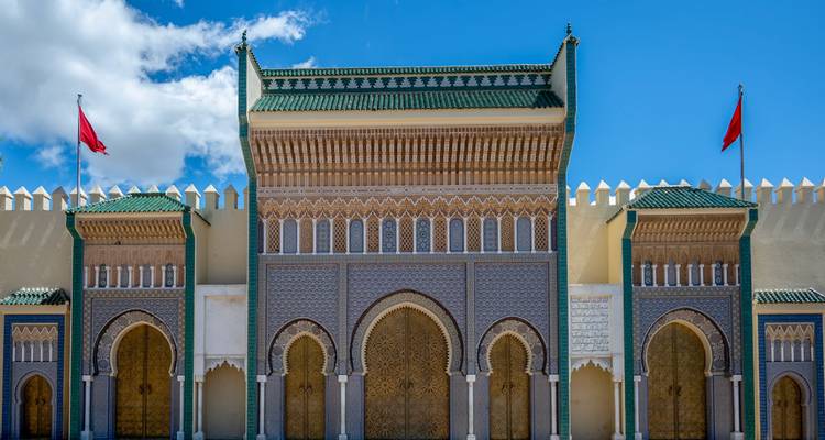 Sierlijk versierde poort van het Koninklijk Paleis met Marokkaanse vlaggen en ingewikkelde tegelpatronen onder een blauwe hemel