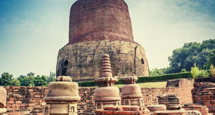 Ancient brick Dhamek Stupa towering over stone relics in Sarnath