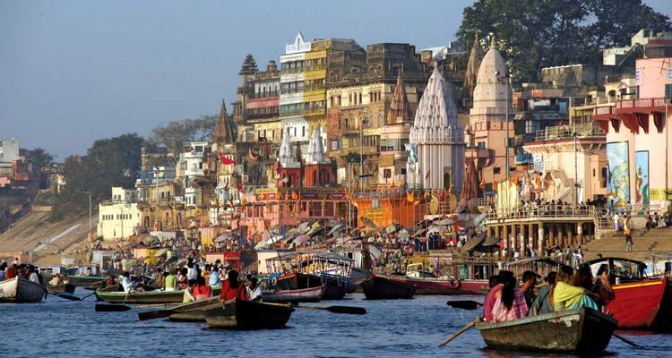 Bustling Varanasi ghats with colorful temples, boats and crowds lining the Ganges