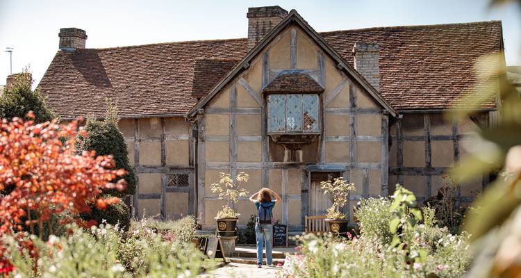 Ein Reisender fotografiert Shakespeares Fachwerkgeburtshaus inmitten blühender Bauerngärten in Stratford-upon-Avon.