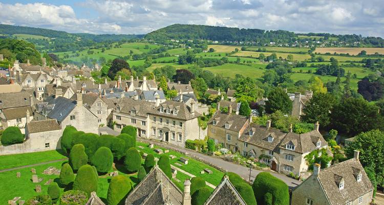 Typisches Cotswolds-Dorf mit honigfarbenen Steinhäusern schmiegt sich in die sanft hügelige grüne englische Landschaft.