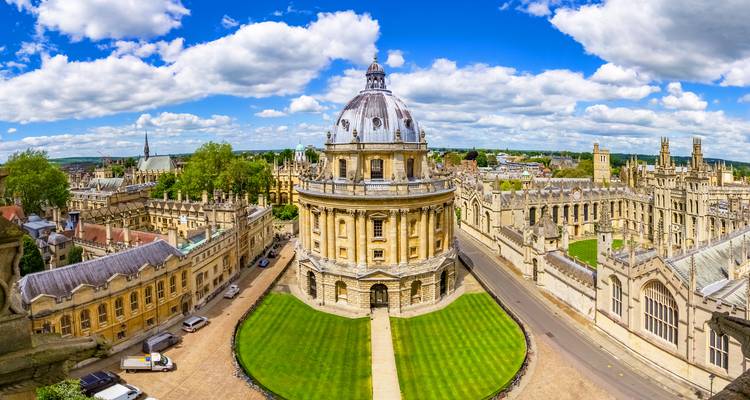 Ein Panoramablick auf die kreisrunde Radcliffe Camera Bibliothek, umgeben von historischen Oxford University Gebäuden unter einem strahlend blauen Himmel.