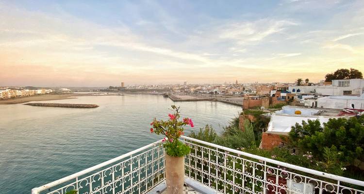Terrasaussicht over rivier en witgekalkt oude stad bij pastelkleurige zonsondergang