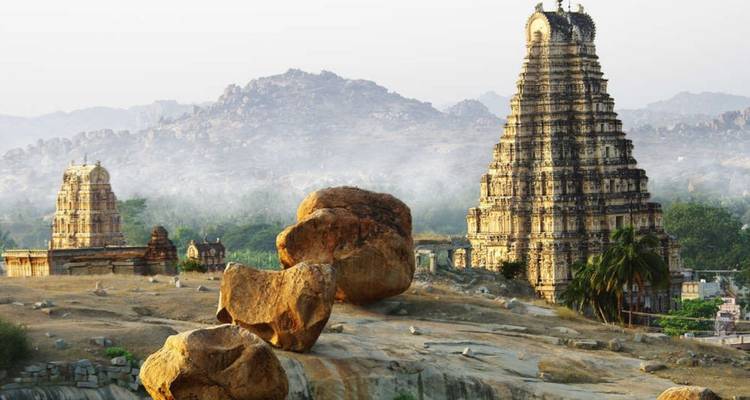 La antigua torre del templo de piedra de Hampi se alza entre un paisaje surrealista sembrado de rocas al amanecer.