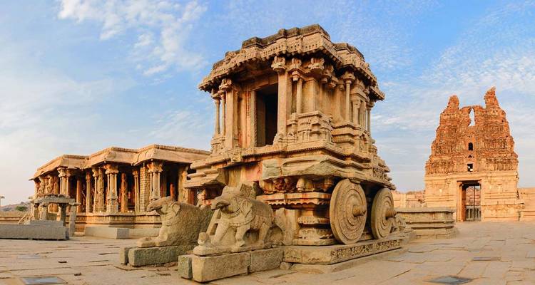 Carro de piedra y ruinas del templo de Hampi bajo un cielo azul claro.