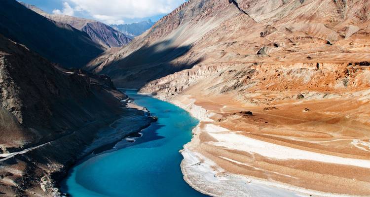Luftaufnahme eines türkisfarbenen Flusses, der sich durch ein karges Himalaya-Tal schlängelt