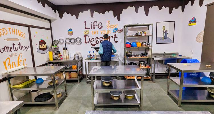Una persona trabaja sola en una cocina de postres muy decorada con arte mural divertido sobre repostería.