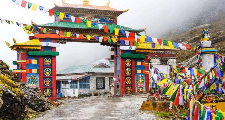 Buntes Himalaya-Tor, geschmückt mit Gebetsfahnen, steht an einer nebligen Bergstraße.