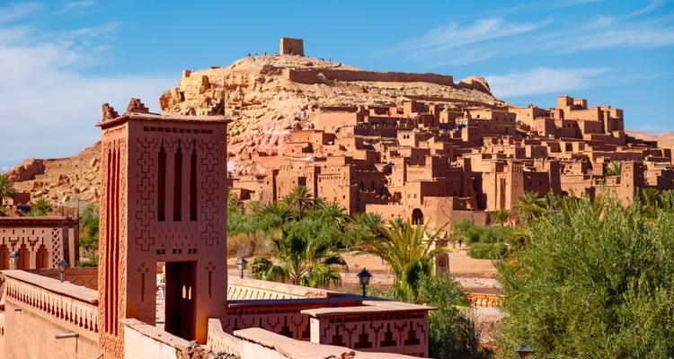 Village fortifié emblématique d'Aït-ben-Haddou avec des bâtiments en briques de terre empilés sous un grenier au sommet d'une colline.