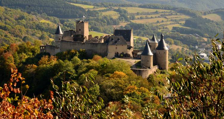 Le château de Vianden, perché sur une colline de conte de fées, entouré de forêts automnales et de vallées onduleuses.