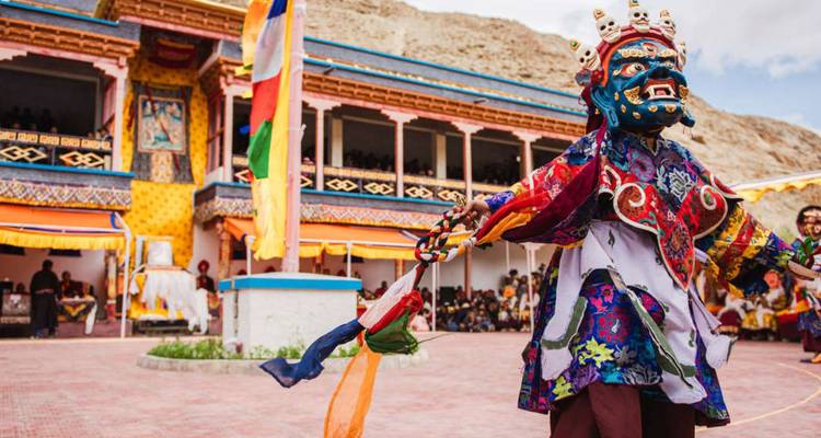 Bunter maskierter Tänzer führt einen traditionellen buddhistischen Cham in einem Klosterhof während eines Festivals auf.