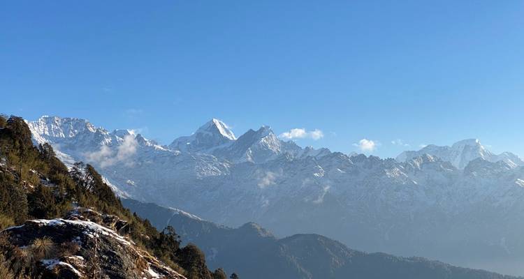 Uitgestrekt panorama van besneeuwde Himalaya-bergkammen verlicht door helder ochtendlicht.