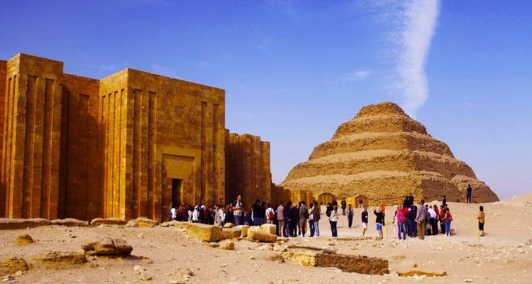 Toeristen verzamelden zich voor de Trappiramide van Saqqara onder een heldere blauwe hemel in de woestijn.