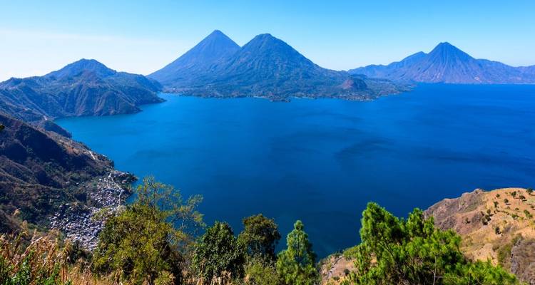 Panorama saisissant du lac Atitlán d'un bleu profond encerclé par de parfaits cônes volcaniques
