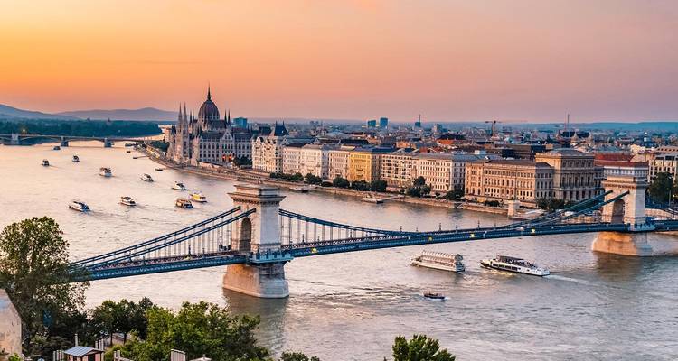 Vista panorámica del Puente de las Cadenas de Budapest atravesando el río Danubio al atardecer con el edificio del Parlamento de fondo.